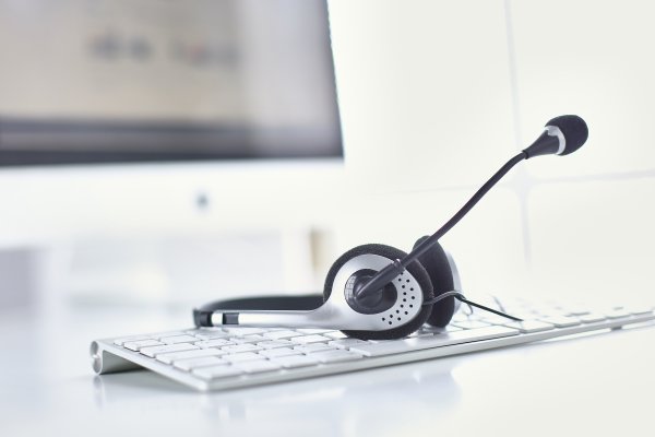 voip services tips headset on computer keyboard monitor in the background